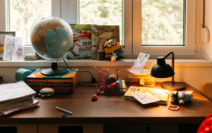 Desk with globe and toys beside books and papers in a well lit room